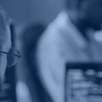 Developer writing database code at a workstation, representing Snowflake stored procedures and SQL scripting