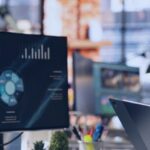 Kanerika vs Sigmoid blog banner showing a data professional reviewing analytics dashboards on office monitors.