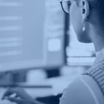Kanerika banner for AI agent evaluation, an analyst reviewing code and test dashboards on screen