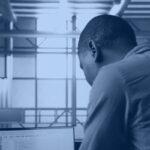 Data engineer reviewing ETL process optimization code on a laptop in a data center, Kanerika navy duotone hero banner
