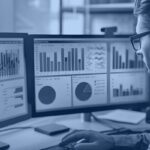 Data analyst reviewing multiple BI dashboards on dual monitors, representing a Snowflake semantic layer unifying metrics across tools