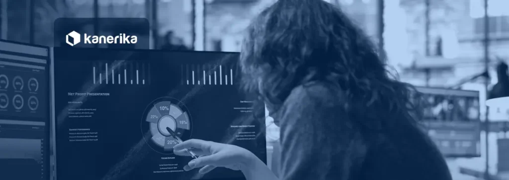 Analyst pointing at an AI performance metrics dashboard with charts on a monitor, Kanerika blog banner