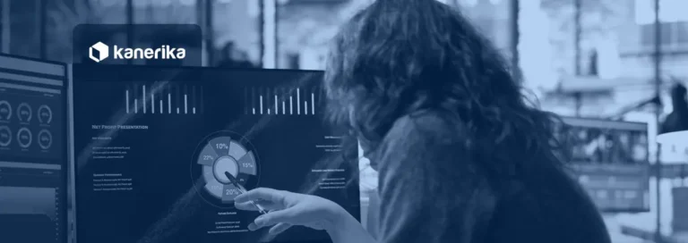Analyst pointing at an AI performance metrics dashboard with charts on a monitor, Kanerika blog banner