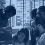 Software engineering team gathered around monitors reviewing code, representing engineering productivity tools for engineering leaders