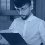 Analyst reviewing printed enterprise reports and charts, banner for Kanerika's guide to enterprise reporting tools