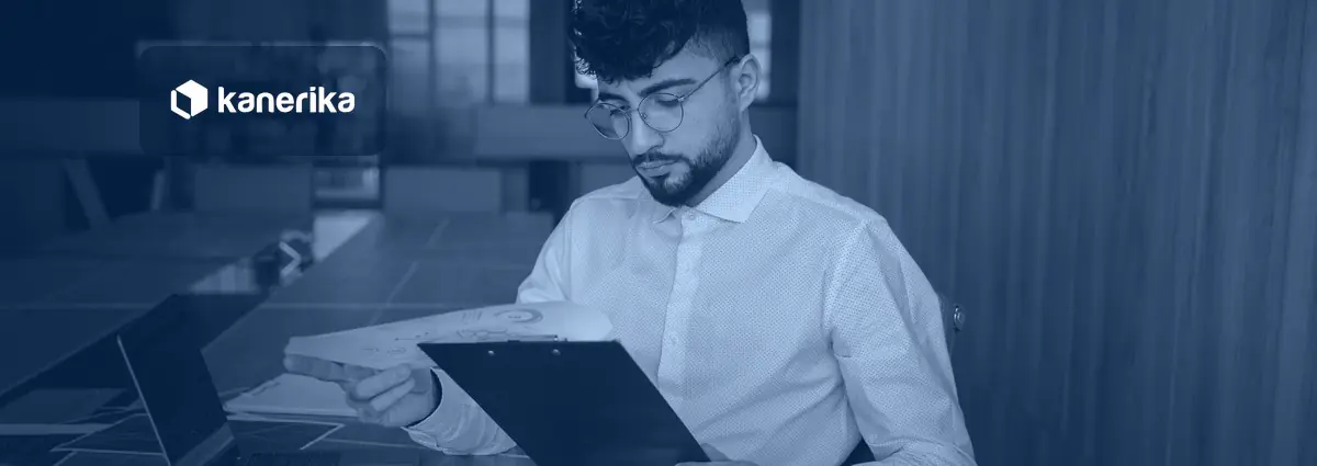 Analyst reviewing printed enterprise reports and charts, banner for Kanerika's guide to enterprise reporting tools