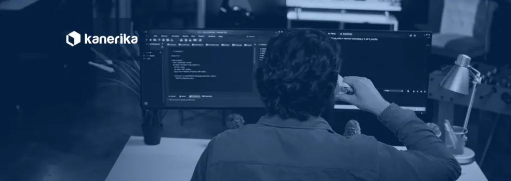 Software developer writing code on a dual-monitor setup, representing PySpark notebook development for Microsoft Fabric Warehouse