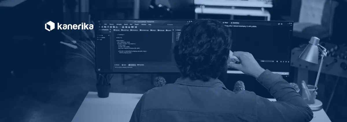 Software developer writing code on a dual-monitor setup, representing PySpark notebook development for Microsoft Fabric Warehouse