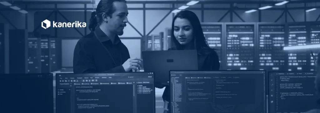 Two data engineers reviewing code on a laptop in a server room while planning a Unity Catalog migration on Databricks
