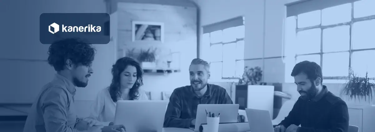 Four colleagues around a table with laptops in a bright co-working office, tinted navy blue with the Kanerika logo, for a post on AI for startups