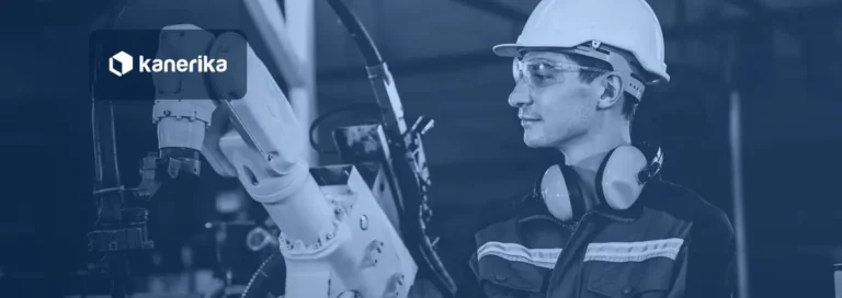 Kanerika banner for AI in robotics: an engineer in a hard hat and safety glasses inspects an industrial robot arm on a factory floor, shown in navy tones