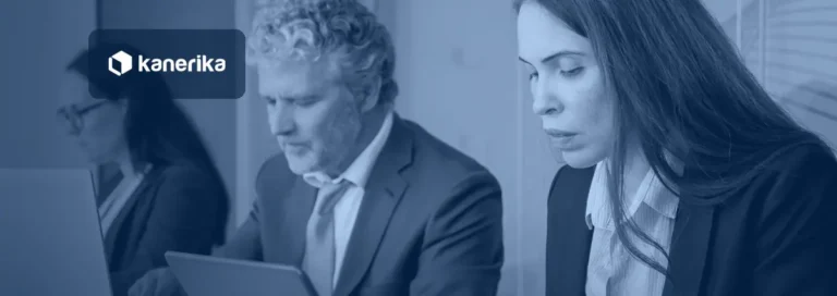 Colleagues working side by side on laptops and a tablet in a modern office, reviewing automated and AI-driven workflows, Kanerika banner for AI vs automation intelligence