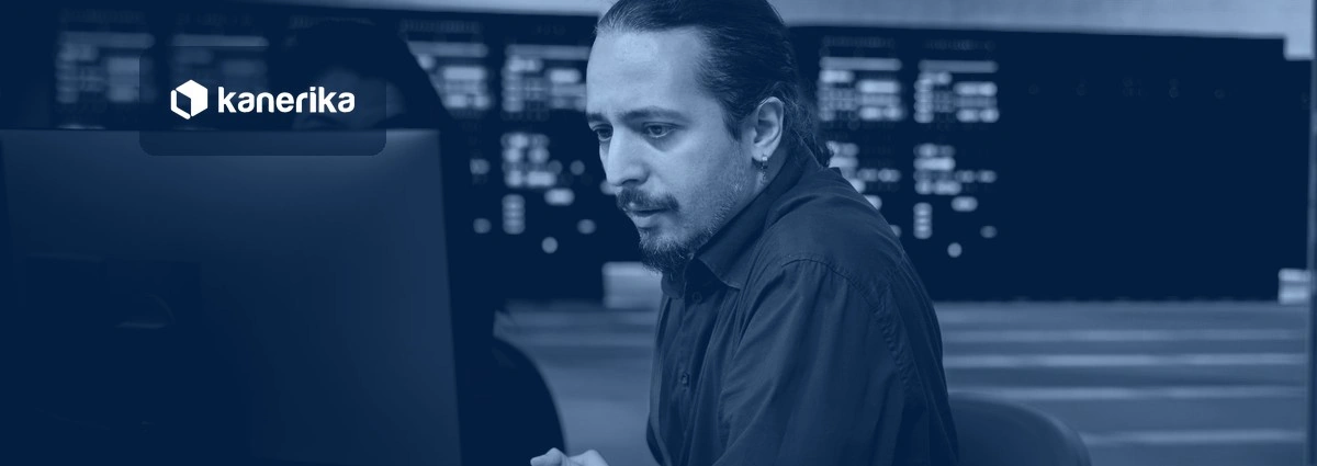 IT operations engineer investigating system errors at a workstation in a command center, navy-toned Kanerika banner for AIOps tools