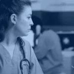 Nurse in blue scrubs reviewing an appointments list on a clinic computer monitor, Kanerika banner for automation in healthcare