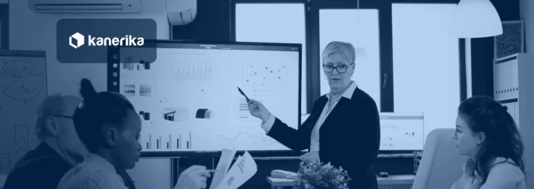 Analyst presenting reporting dashboards and charts to a team on a large screen, navy-toned Kanerika banner for Cognos to Power BI migration