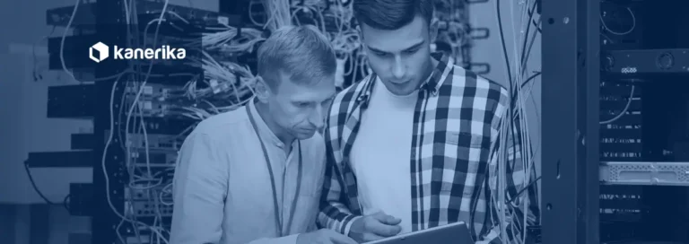 Two network engineers reviewing a tablet beside a telecom equipment rack with cabling, representing data analytics in telecom