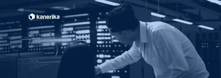 Two data center engineers reviewing code on a monitor beside server racks, Kanerika banner for data conversion vs data migration