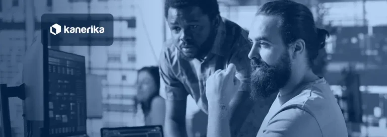 Two data engineers reviewing pipeline and data integration workflows on monitors in a modern office