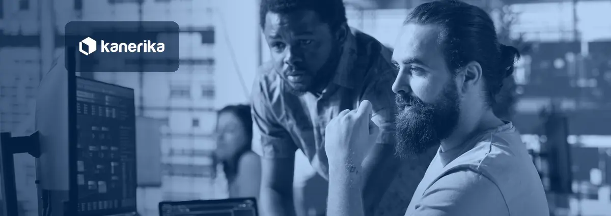 Two data engineers reviewing pipeline and data integration workflows on monitors in a modern office