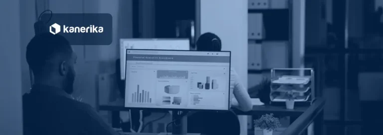 Two analysts at a modern office desk reviewing a data dashboard scoreboard with bar and cash flow charts on a monitor