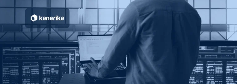 Engineer testing data migration on a laptop inside a data center aisle, shown in a navy blue tint with the Kanerika logo