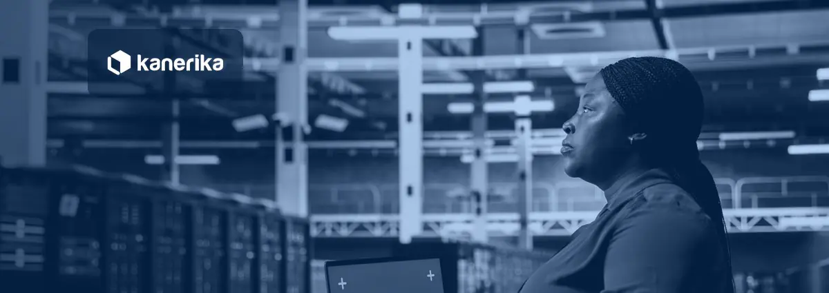 Data center engineer looking up from her laptop in a server room, representing monitoring of data pipelines