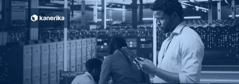 Data center engineer checking a tablet beside server racks while colleagues review systems