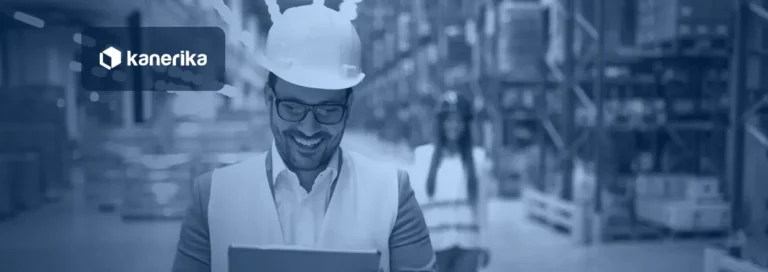 Smiling warehouse manager in a hard hat and vest reviewing shipment status on a tablet in a large distribution center