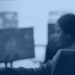 Enterprise manager reviewing dashboards on several monitors in a monitoring room, illustrating oversight of an enterprise LLM