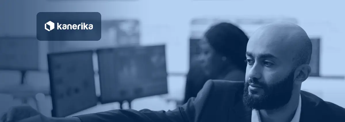 Enterprise manager reviewing dashboards on several monitors in a monitoring room, illustrating oversight of an enterprise LLM