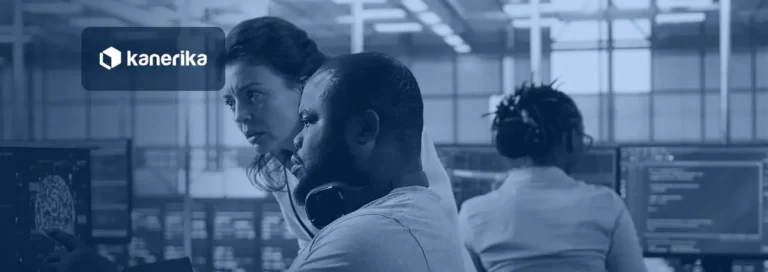 Two engineers leaning in to review model monitoring screens in a data center control room while a colleague works on code in the background