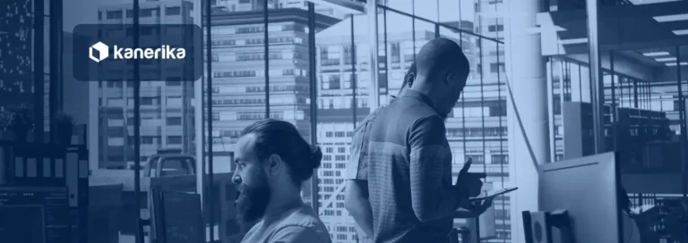 Two colleagues in a modern office with city skyline windows reviewing work on screens, Kanerika banner for RPA for enterprise