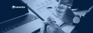 Two finance professionals reviewing charts and reports on paper next to a laptop, a blue-toned photo for an article on RPA in finance