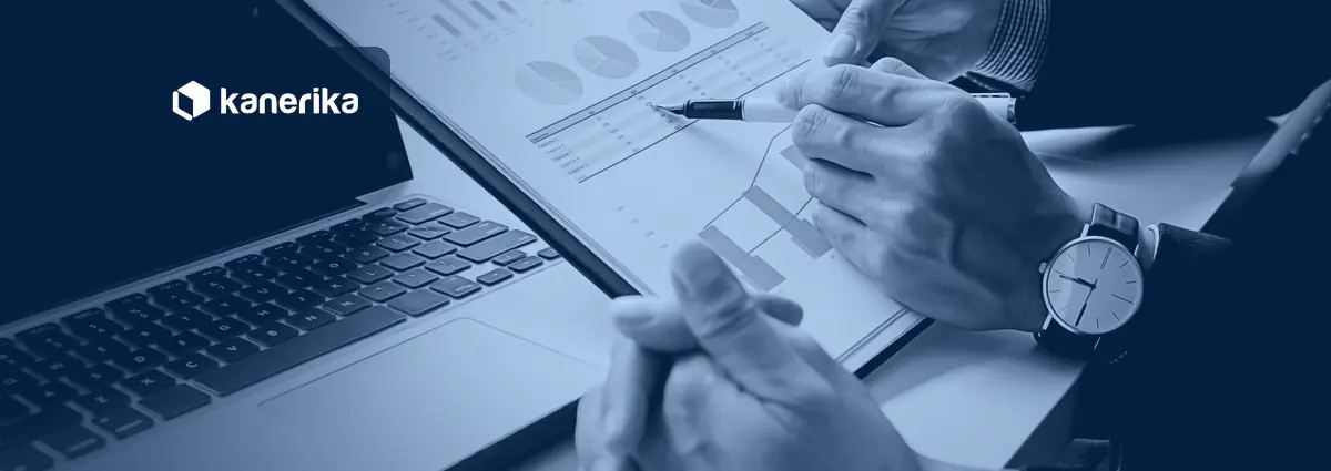 Two finance professionals reviewing charts and reports on paper next to a laptop, a blue-toned photo for an article on RPA in finance